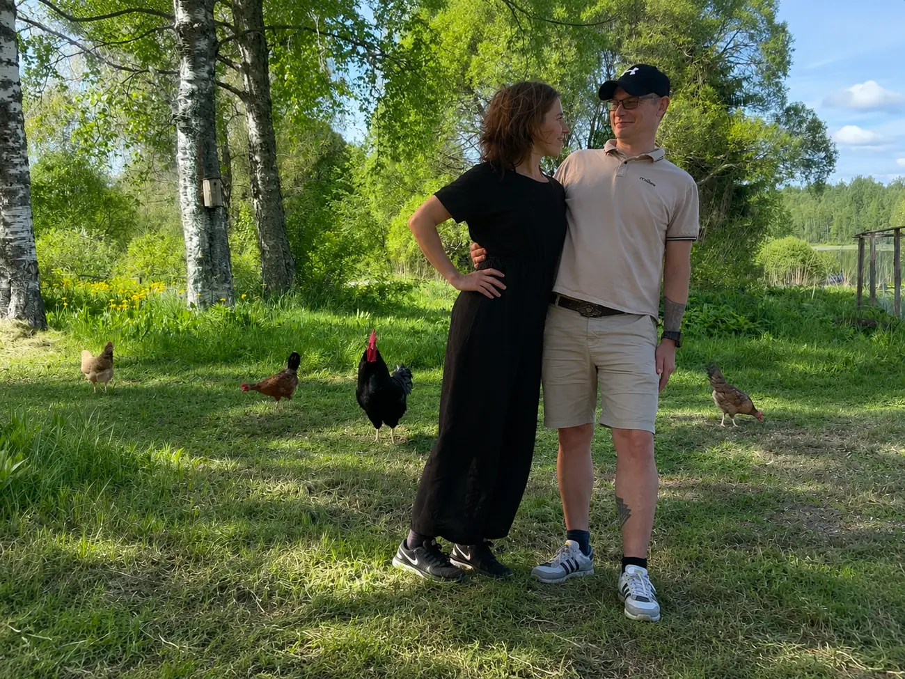 Jani and Kristiina on the farm in summer sunshine, with their chickens behind them